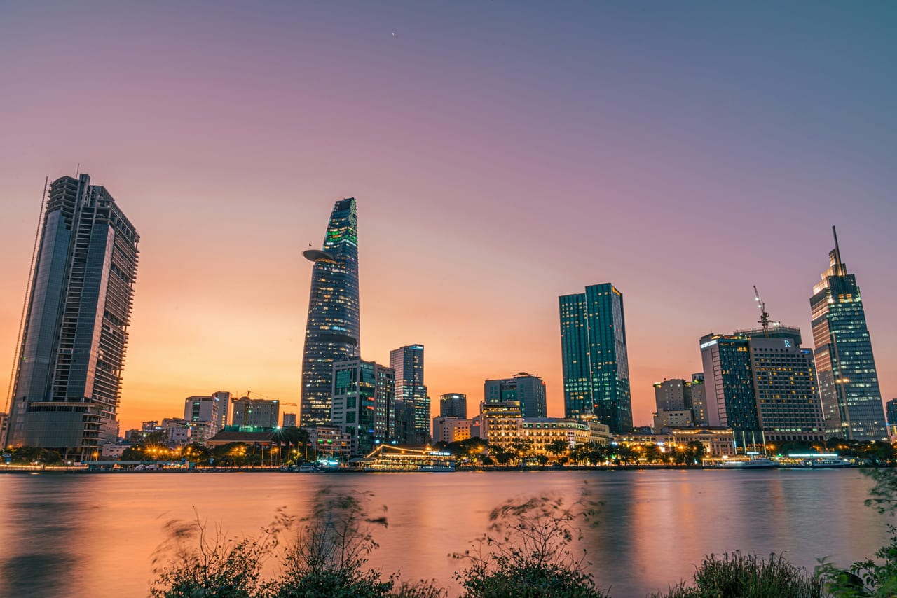 Các tòa nhà cao tầng ven sông Sài Gòn lúc hoàng hôn, mặt nước phản chiếu ánh hồng